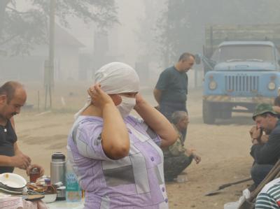 Mit einer Maske versucht diese Frau, sich vor dem stark gesundheitsgefährdenden Rauch zu schützen. Schutz vor dem Rauch