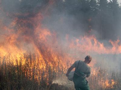 Mit Wasser aus einer großen Schüssel versucht ein Helfer, meterhohe Feuerwalzen zu löschen. Verzweifelte Löschversuche