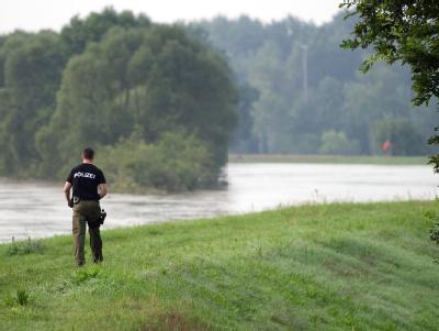 Ein Polizeibeamter geht über den Deich unweit von Klein Bademeusel,. Neiße
