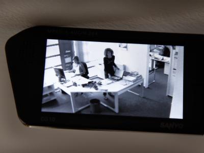 Eine Videokamera zeichnet in einer gestellten Szene die Arbeit in einem Büro auf. Video-Überwachung
