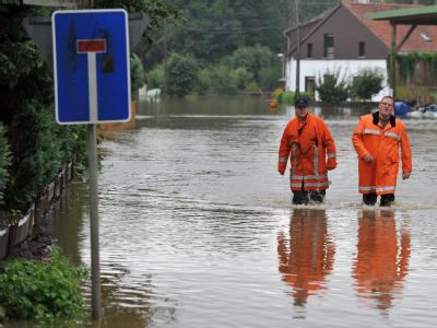 Zwei Feuerwehrleute waten im Landkreis Osnabrück durch eine überschwemmte Straße. Überschwemmte Straße