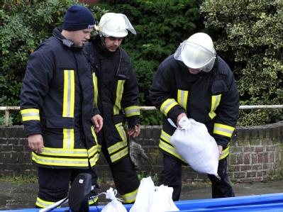 Feuerwehrmänner laden in Ochtrup-Langenhorst im Kreis Steinfurt Sandsäcke in ein Kanu. Unwetter-Einsatz in Nordrhein-Westfalen