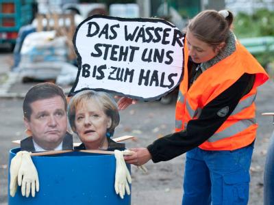 Eine Aktivistin der Protestbewegung Parkschützer befestigt in Stuttgart ein Bild von Bundeskanzlerin Angela Merkel und Baden-Württembergs Ministerpräsident Stefan Mappus (beide CDU). Mappus und Merkel zeigen bei den Protesten um das umstrittene Bahnprojek Mappus und Merkel
