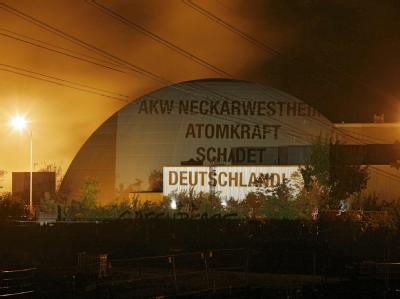 Der Spruch «AKW Neckarwestheim: Atomkraft schadet Deutschland» ist in Neckarwestheim auf das Reaktorgebäude des AKW Neckarwestheim projiziert. Leuchtender Protest gegen Atomkraft