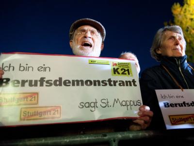 Gegner des Bahnprojekts Stuttgart 21 halten am Freitagabend im Stuttgarter Schlossgarten ein Plakat mit der Aufschrift «Ich bin ein Berufsdemonstrant» in den Händen. Stuttgart 21 - Freitagsdemonstration