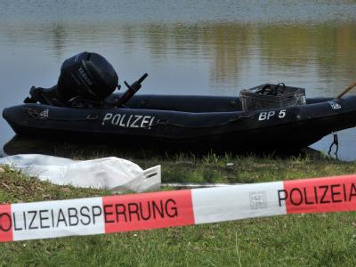 Ein Leichensack mit Leichenteilen liegt am Ufer eines Badesees bei Erlabrunn bei Würzburg hinter einer Polizeiabsperrung. Ein Mann hat am Sonntagnachmittag mehrere Leichenteile in einem Badesee gefunden. Leichenteile entdeckt