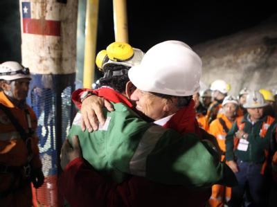 Der chilenische Präsident Sebastian Piñera (r) umarmt Luis Urzua, der als letzter aus dem unterirdischen Gefängnis befreit wurde. Alle 33 chilenischen Bergleute gerettet