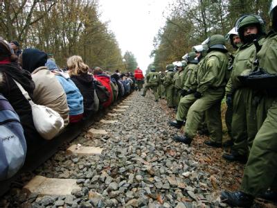 Castorgegner sitzen bei Hitzacker auf den Bahngleisen der Transportstrecke zwischen Lüneburg und Dannenberg - bewacht von zahlreichen Polizeibeamten (Archivfoto vom 08.11.2004). Konfrontation