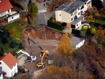 Die Luftaufnahme zeigt Bagger beim Verfüllen des Erdkraters in der Walter-Rathenau-Straße im südthüringischen Schmalkalden. Erdfall in Schmalkalden