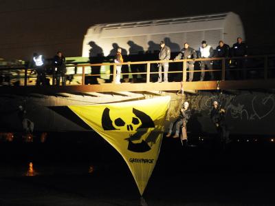 Ein Zug mit 11 Castor-Behältern verlässt den Bahnhof im badischen Kehl. Unter der Brücke haben sich Greenpeace-Aktivisten angeseilt. Castor-Zug