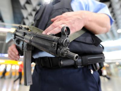 Mit einer Maschinenpistole bewaffnet sichert ein Beamter der Bundespolizei einen Flughafen. Maschinenpistole