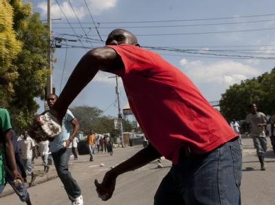 Ein Haitianer schleudert in Port au Prince einen Stein auf die dort stationierten UN-Blauhelme. Unruhen in Port-au-Prince
