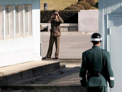 Ein nordkoreanischer Soldat (hinten) betrachtet mit einem Fernglas einen südkoreanischen Soldaten, der an der Demarkationslinie der «Entmilitarisierten Zone» im Grenzort Panmunjom Wache steht (Archivbild). Grenze zwischen Nord- und Südkorea
