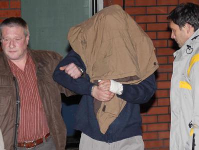 Der mutmaßliche Doppelmörder wird von Polizeibeamten abgeführt. Mutmaßlicher Doppelmörder