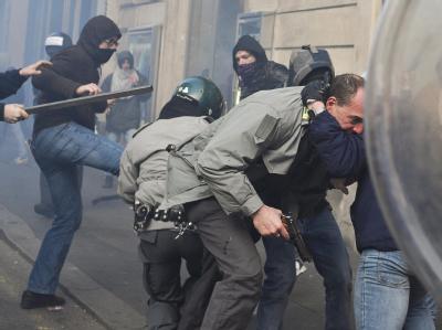 Ein von Autonomen attackierter Polizist zieht seine Waffe. Gewalt