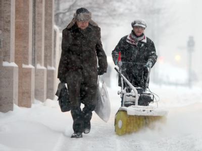 Eine Helferin befreit im Berliner Stadtteil Mitte den Gehweg vom Schnee. Schnee in Berlin