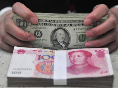 Ein Bankangestellter zählt Dollar- und Yuan-Noten. China vergibt mehr Kredite an die Dritte Welt als die Weltbank. Dollar und Yuan