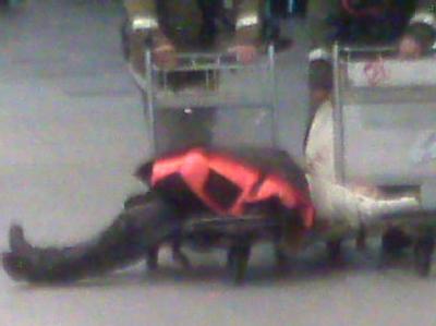 Ein Mensch liegt im Flughafen Domodedowo in Moskau auf einem Gepäckwagen. Terroropfer