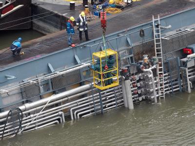 Bergungskräfte begutachten die Rohrleitungen auf dem Oberdeck des auf dem Rhein gekenterten Schwefelsäure-Tankschiffs Waldhof. Explosionsgefahr
