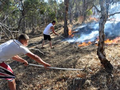 Zwei Australier versuchen die sich ausbreitenden Flammen zu stoppen. Brandbekämpfung