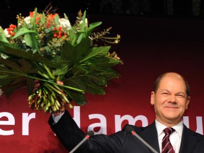 Der Spitzenkandidat der Hamburger SPD, Olaf Scholz, winkt mit einem Blumenstrauß seinen Parteianhängern. Scholz