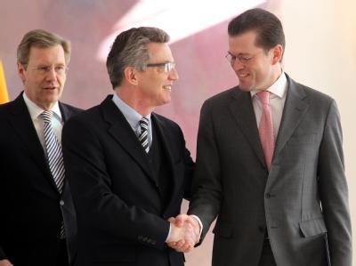 Der neue Verteidigungsminister Thomas de Maizière (m) gibt seinem Amtsvorgänger Karl-Theodor zu Guttenberg die Hand. Bundespräsident Christian Wulff (l) hatte zuvor zu Guttenberg die Entlassungsurkunde überreicht. Wulff, de Maizière, Guttenberg