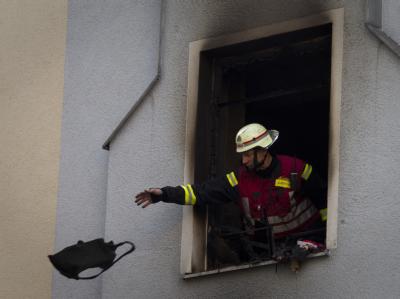 Ein Feuerwehrmann wirft nach einem Brand einen Gegenstand aus dem Unglückshaus. Drei Tote nach Brand