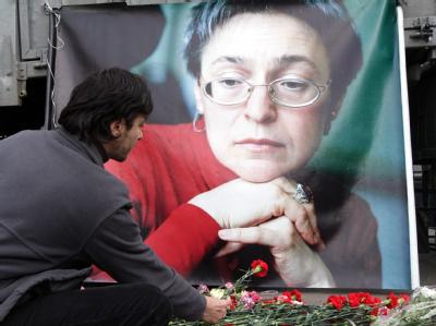 Ein Mann legt an einem Porträt von Anna Politkowskaja in Moskau eine Nelke nieder (Archivfoto). Trauer um Politkowskaja