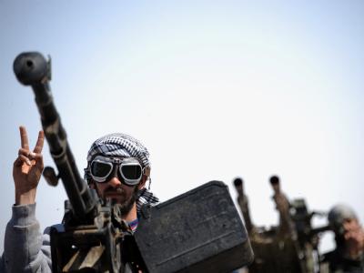 Ein libyscher Rebell hinter einem Maschinengewehr macht das Siegeszeichen. Rebellen in Libyen