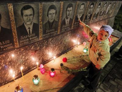Ein kleiner Junge zeigt auf ein Bild einer «Liquidatoren»-Galerie auf einem Denkmal in Kiew. Seit Monaten wehren sich Strahlenopfer gegen die Kürzung von Sozialleistungen. Archivfoto: Sergey Dolzhenko 25 Jahre Tschernobyl