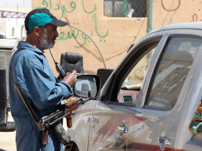 Ein libyscher Aufständischer kontrolliert am Grenzposten Wassin ein Auto. Kämpfe in Libyen gehen weiter