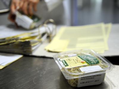 Eine Packung mit Bockshornkleesprossen steht auf einem Labortisch. Sprossen werden auf EHEC untersucht