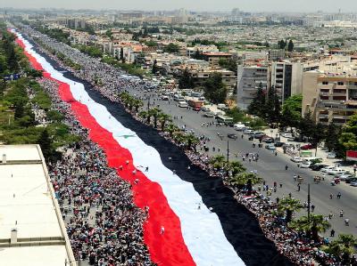 Demonstranten in Damaskus bekunden mit einer Landesflagge ihre Unterstützung für Syriens Präsident al-Assad. Sympathiewelle für al-Assad