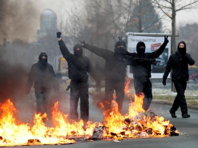 Autonome der linken Szene posieren am 19.02.2011 am Rande einer Neonazi-Kundgebung in Dresden hinter einer brennenden Barrikade. Verfassungsschutzbericht 2010