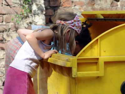 Zwei Kinder wühlen in Berlin-Kreuzberg in einer Mülltonne. Foto: Britta Pedersen/Archiv Wühlen im Müll