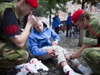 Dieser Mann verletzte sich am rechten Bein - zwei Militärpolizisten leisten Erste Hilfe. Erste Hilfe