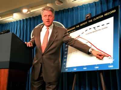 US-Präsident Bill Clinton zeigt am 25.10.1995 auf eine Tafel, die anzeigt, wie unter seiner Regierung das US-Haushaltsdefizit in den letzten drei Jahren gut um die Hälfte gesunken ist. Clinton 1995