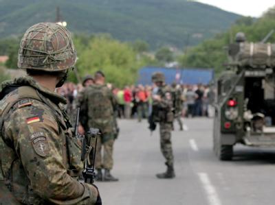 Ein deutscher Soldat und slowenische Soldaten der KFOR am 29.07.2011 vor einer Straßenblockade durch eine Menschenmenge in Rudare (Kosovo). Straßenblockade im Kosovo