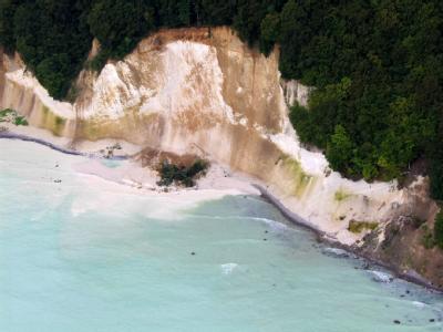 Milchig trüb ist das Wasser der Ostsee nach einem Kreideabbruch auf der Insel Rügen, Bäume liegen vor dem Felsen im Wasser. Neue Kreideabbrüche auf Rügen