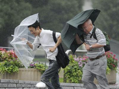 Zwei Männer kämpfen in Tokio mit ihren Regenschirmen gegen den Taifun Roke an. Taifun Roke