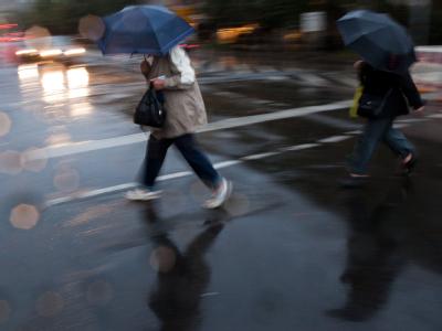 Passanten eilen unterm Regenschirm durch Berlin. Foto: Michael Kappeler Regen in Berlin