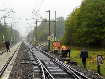 Polizisten und Mitarbeiter der Deutschen Bahn untersuchen bei Falkensee ein Leitungskasten an den Bahngleisen. Foto: Holger Kohl Brandsätze an Gleisen entdeckt