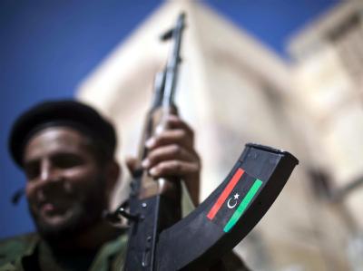 Ein lächelnder Gaddafi-Gegner zeigt seine Waffe. Noch sind die genauen Todesumstände Gaddafis unklar. Foto: Guillem Valle Waffe