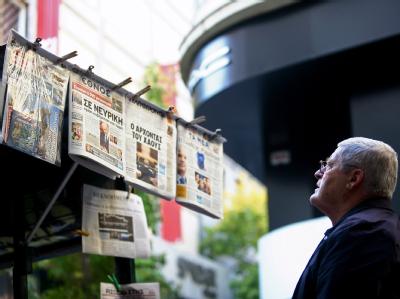 Ein Passant studiert die Zeitungsüberschriften an einem Kiosk in Athen. Sie stellt die Griechen vor die Wahl: Entscheidet euch, ob ihr im Euroland bleiben wollt. Foto: Alkis Konstantinidis Zeitungskiosk in Athen
