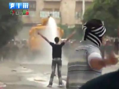 Das TV-Bild des Shaam News Network vom 17. Oktober zeigt einen syrischen Demonstranten vor einem Wasserwerfer, während ein weiterer Demonstrant im Vordergrund ein Stein wirft. Foto: Shaam News Network Assad-Regime zeigt weiter Härte