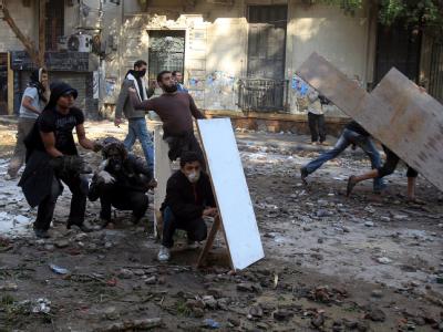 Junge Männer werfen Steine auf Sicherheitskräfte und schützen sich mit Brettern. Foto: Khaled Elfiqi Ausschreitungen in Kairo