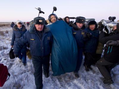 Russische Sicherheitskräfte tragen den japanischen Astronaut Satoshi Furukawa kurz nach der Landung zum Medizincheck. Foto: NASA/Bill Ingalls Auf dem Weg zum Medizincheck