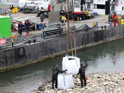 Wasserbauer errichten am Rheinufer in Koblenz einen Damm aus Sandsäcken um den Fundort einer Luftmine aus dem Zweiten Weltkrieg. Foto: Thomas Frey Vorarbeiten zur Bombenentschärfung