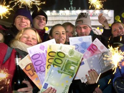 Mit übergroßen Euroschein-Nachbildungen feiern Jugendliche in der Silvesternacht am 1.1.2002 vor dem Brandenburger Tor in Berlin die Einführung der neuen Währung. Foto: Stephanie Pilick/Archiv Euro-Einführung