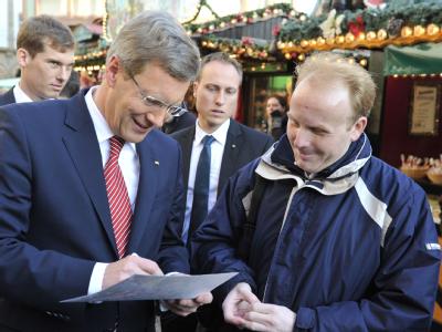 Bundespräsident Christian Wulff gibt auf dem Weihnachtsmarkt vor dem Frankfurter Römer ein Autogramm. Foto: Boris Roessler Christian Wulff in Frankfurt